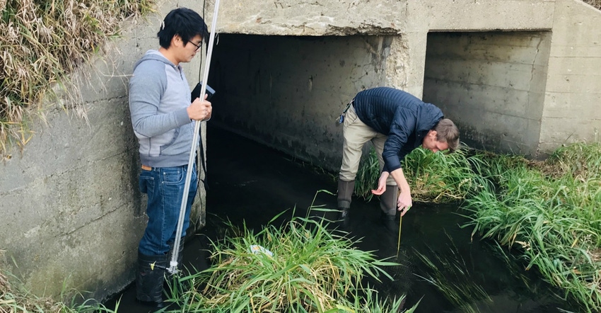 two researchers checking water quality of a stream