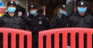 Police officers and security guards stand outside the Huanan Seafood Wholesale Market where the coronavirus was detected in W