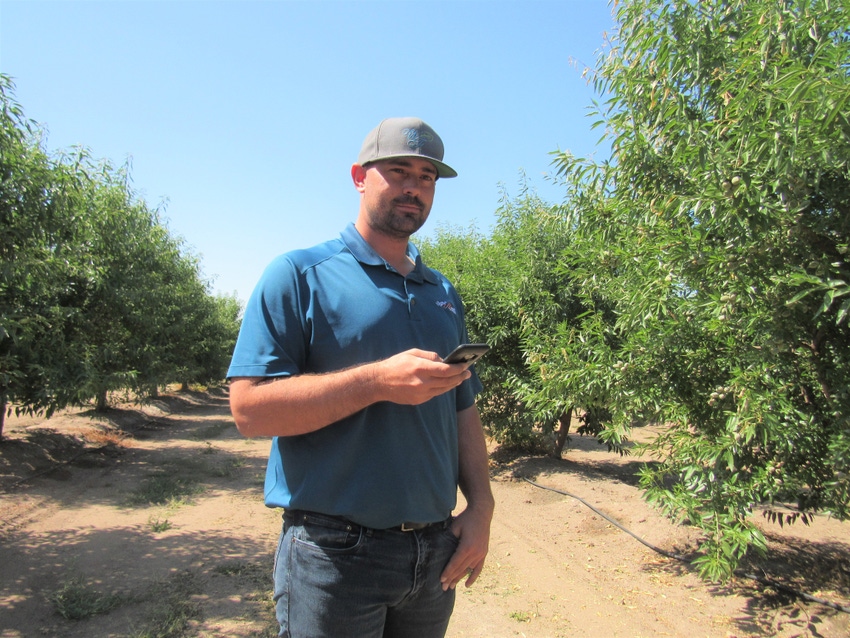 Grower with hand-held device in orchard