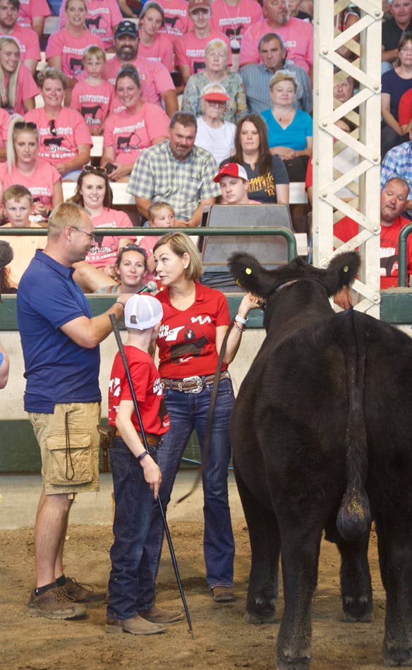Gov. Kim Reynolds talking to a woman and young boy showing a cow