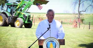 Vilsack speaking at an Iowa farm with tractor in the background