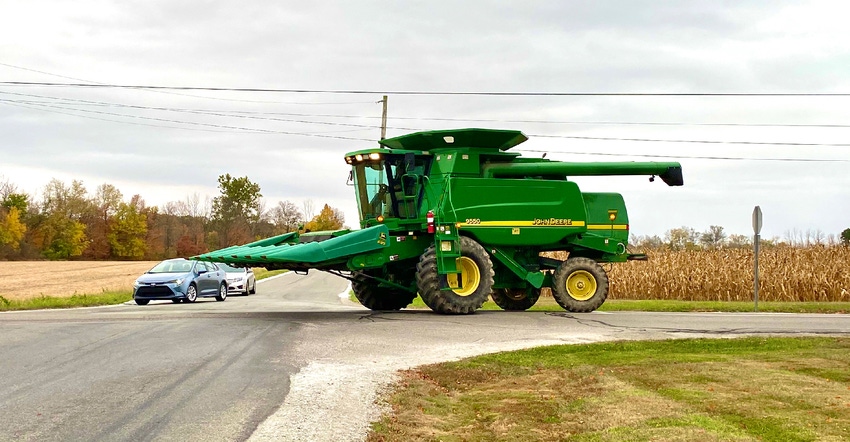 a combine comes in close contact with a car on the road