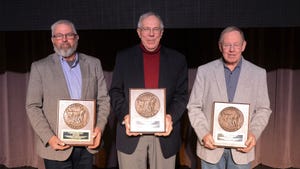Three men each holding plaques pose for a photo