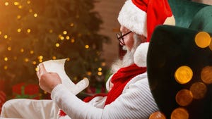  Santa sitting in a chair by a Christmas tree and reading a letter