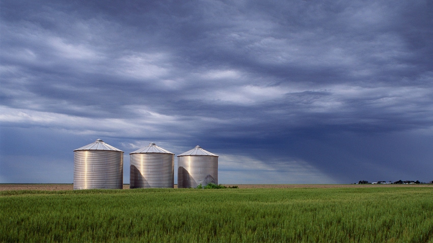 silos in field under cloudy skies