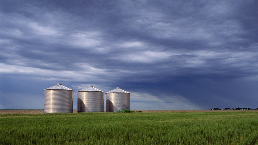 silos in field under cloudy skies silos in field under cloudy skies