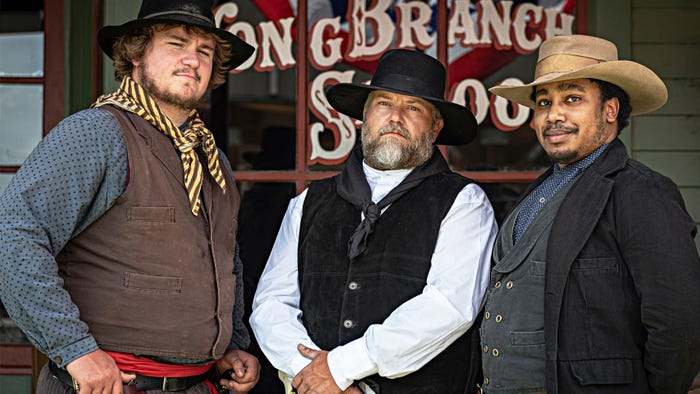 three reenactors in Old West costumes