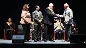 Tom J. Bechman being presented with an award of distinction on a stage