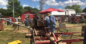 volunteers at Pioneer Village at the Indiana State Fair saw lumber with a sawmill 