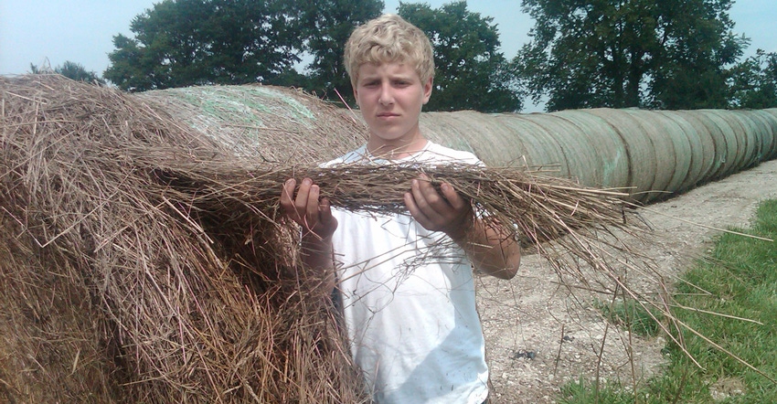 Evan Smith showing a handful of hay to the camera