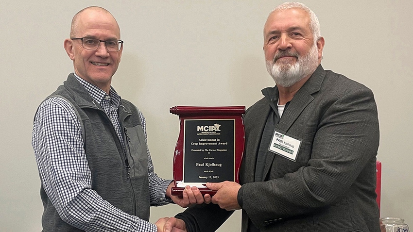 two men holding plaque, shaking hands