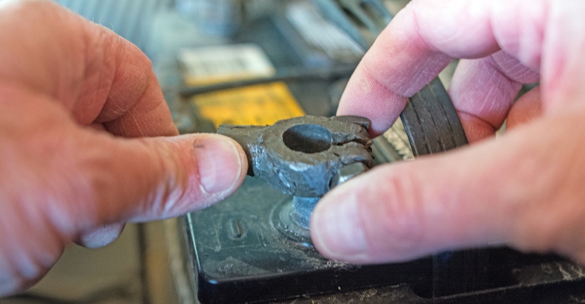 closeup of hands removing a car battery cable