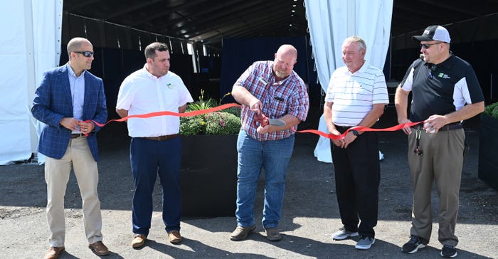 Soybean enthusiasts and show staff cut the ribbon on the soy-based asphalt in the Varied Industries Tent at the Farm Progress Show during media day