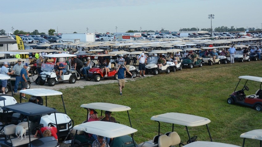 Rows of golf carts parked as people get in and out of them