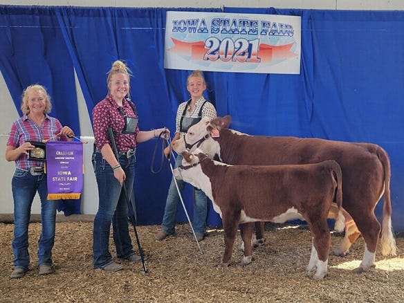 Marie Pagenkopf, Bryanna Smith and Julia Lyons with grand champion miniature Hereford cow-calf pair at Iowa State Fair