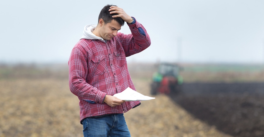 stressed out farmer looking at piece of paper