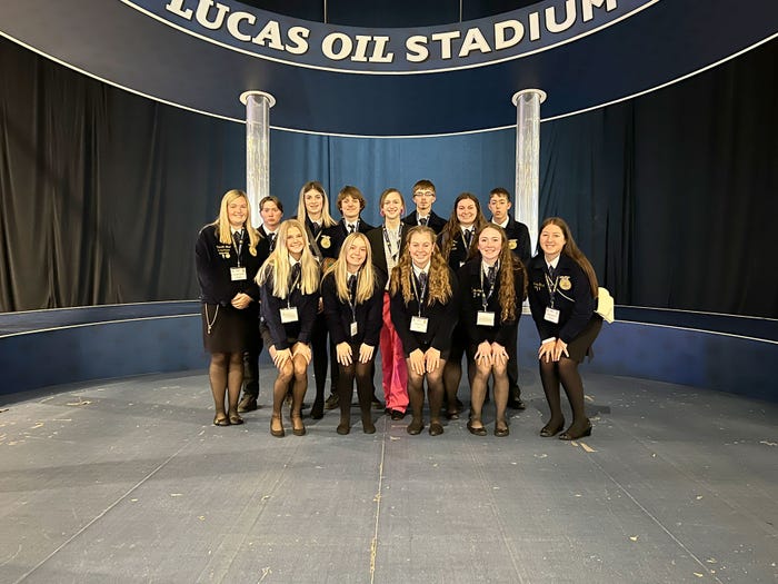 Jeana Curtis and FFA members pose on a stage during a national convention