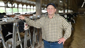 Reid Hoover poses in a barn near Holstein cows