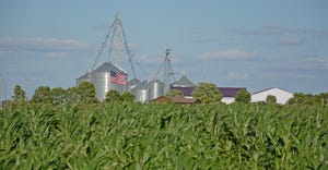corn field with farm in the background