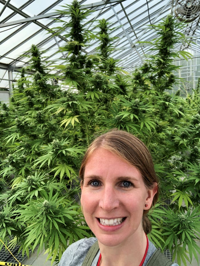A woman taking a selfie photo in front of hemp plants