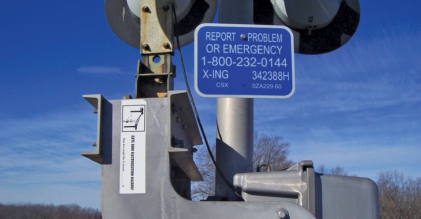 blue sign at railroad crossing
