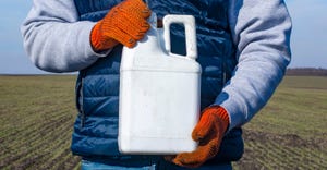 farmer wearing gloves holding pesticide container