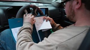 A farmer sitting behind the wheel of a vehicle sorting through paperwork