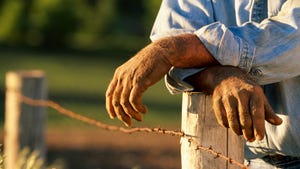 Farmer leaning on fencepost