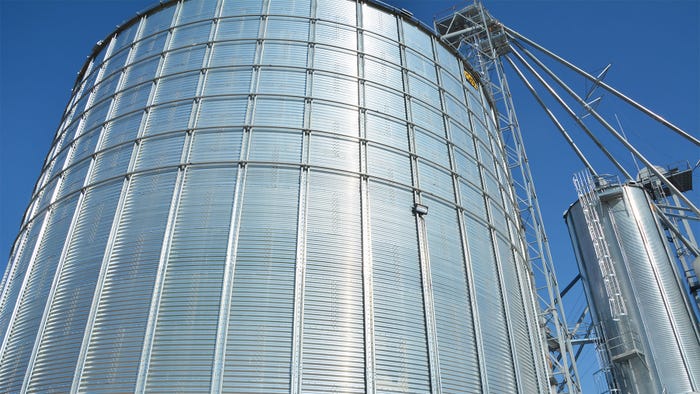 A large grain bin against a blue sky