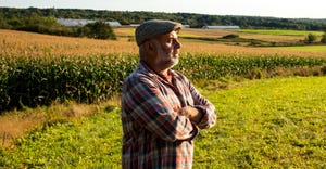 farmer looking out across farmland with look of concern
