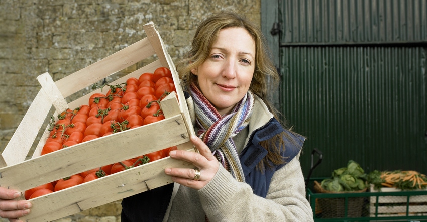 woman holding box of tomatoes