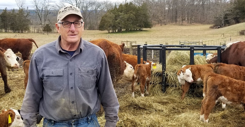 John Wagner, owner of JKW Polled Herefords, stands inside a pen with his herd