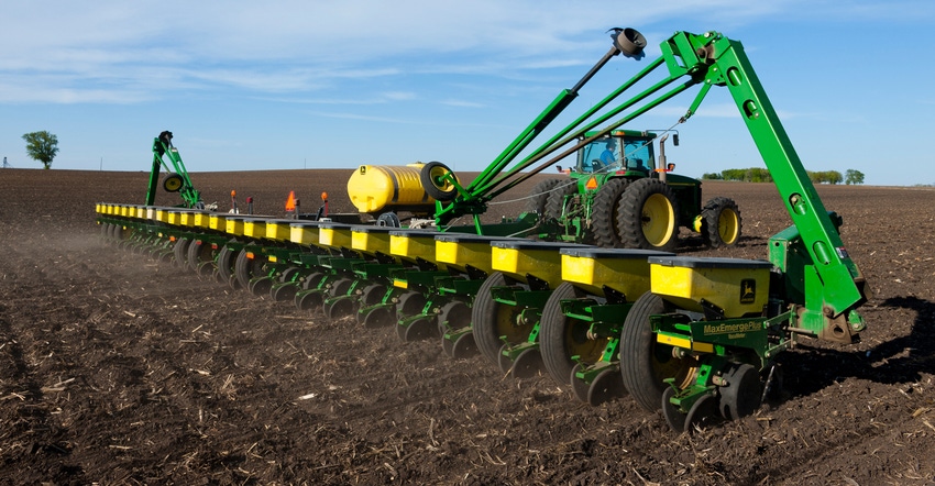 planter driving through field during spring sowing corn seed