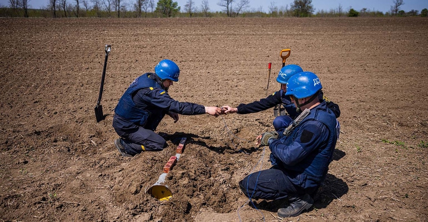 Members of a demining team of the State Emergency Service of Ukraine work to destroy an unexploded missile in a farm field be Members of a demining team of the State Emergency Service of Ukraine work to destroy an unexploded missile in a farm field be