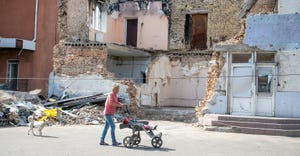 Lady pushing stroller in front of bombed building in Ukraine