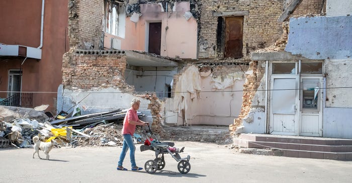 Lady pushing stroller in front of bombed building in Ukraine Lady pushing stroller in front of bombed building in Ukraine