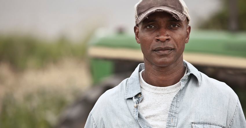 Farmer looking at camera with John Deere in background