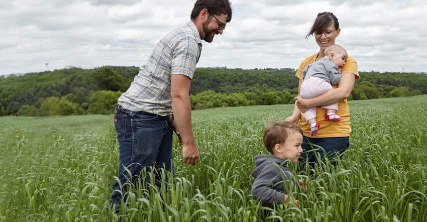 John and Halee Wepking with their two children walking through a wheat field