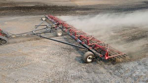 A harrow tractor plowing through a field of soil