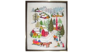 An embroidered winter scene in a wooden frame