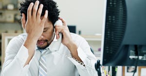 Businessman using phone with hand on forehead. Frustrated man.