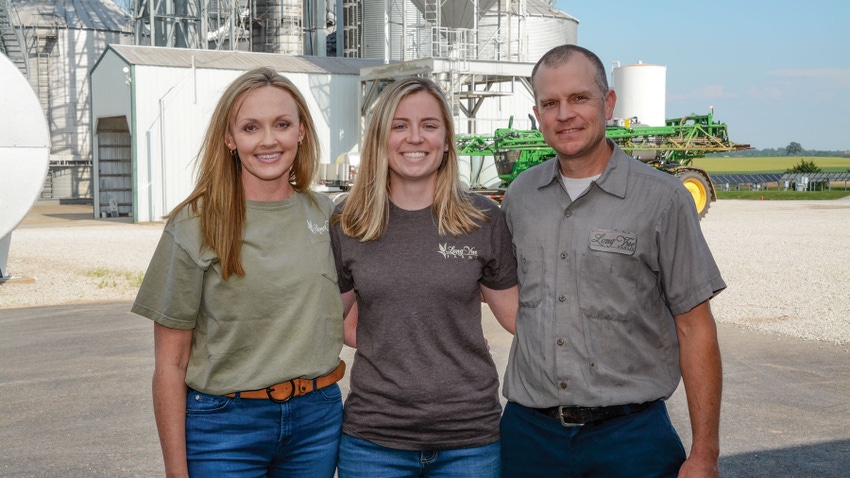 Three women posed in front of grain setup