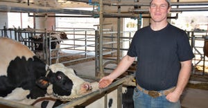 Dairy farmer Dan Lyness stands beside a cow inside his tie-stall barn