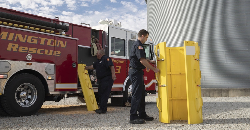 Firemen with a grain bin rescue tube shown at a farm