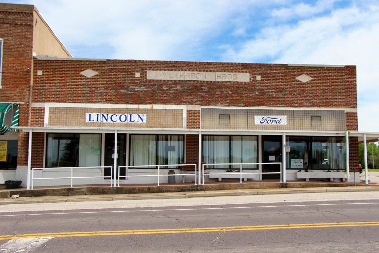 A brick and glass building with the Ford and Lincoln car manufacturer's logos