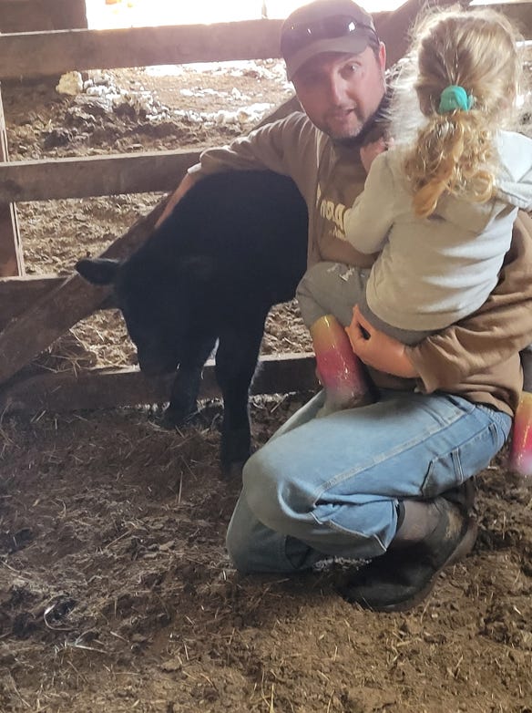 Ryan Ridenour with his daughter and a new calf on the family’s fifth-generation ranch in Cherry County