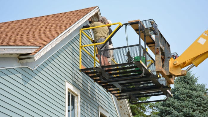 two people in cherry picker working on eaves