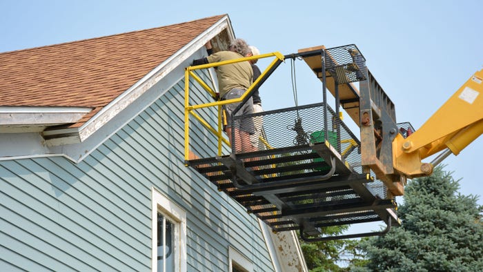 two people in cherry picker working on eaves two people in cherry picker working on eaves