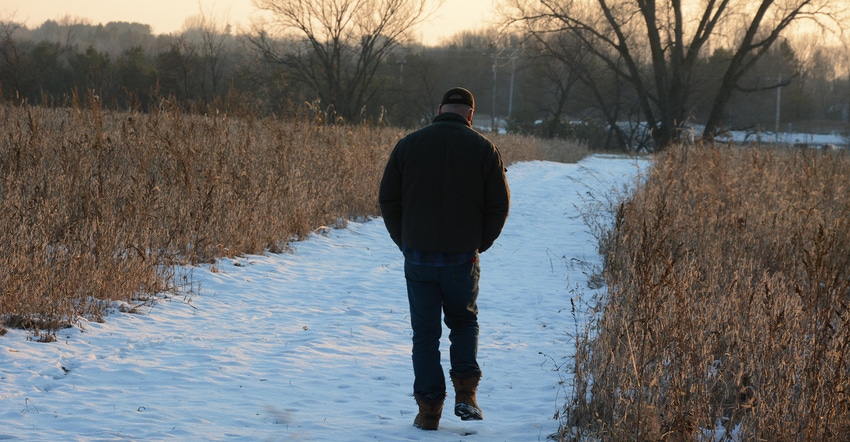 man walking away on rural snow-covered path