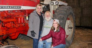 Doug Allen and his two daughters pictured in front of a red tractor